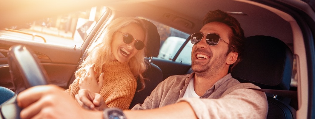 Glückliches Paar im Auto auf einer Autoreise lächelt sich gegenseitig an